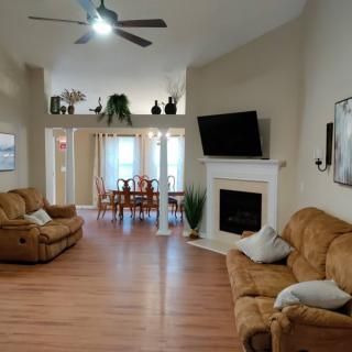 A spacious living room with comfortable sofas, a fireplace topped with a flat-screen TV, and an adjacent dining area.