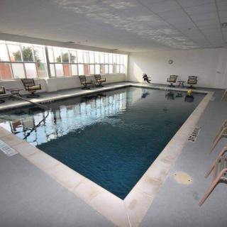 An indoor swimming pool surrounded by chairs and large windows.