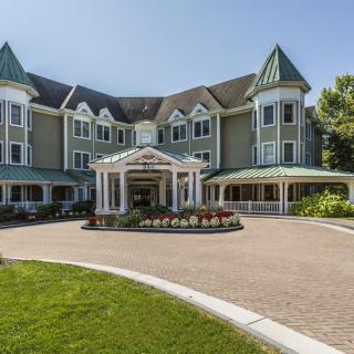 A large, elegant building with a well-maintained driveway and lush landscaping.