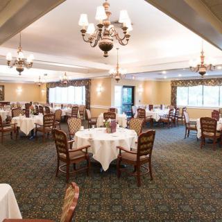 A spacious and elegant dining room with neatly arranged tables and classic chandeliers.