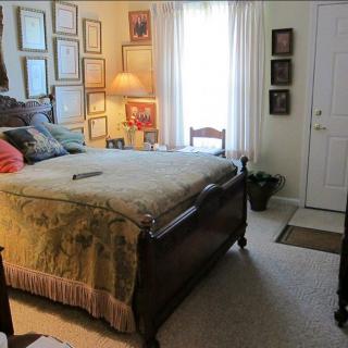 A cozy bedroom with a framed artwork collection and classic furnishings.