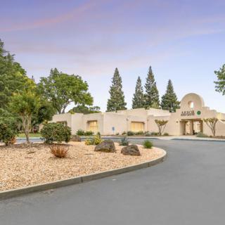A spacious home with a wide driveway, surrounded by well-maintained landscaping and trees.