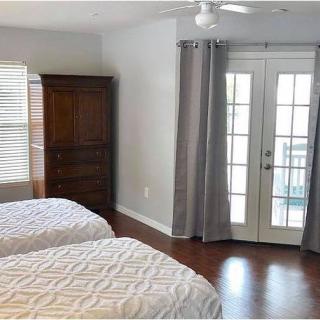 A cozy bedroom with two beds, a wooden wardrobe, and French doors leading to a balcony.