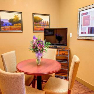 A cozy meeting room with a round table, four chairs, and decorative artwork on the walls.