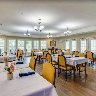 A spacious dining room with elegantly set tables and yellow-upholstered chairs.