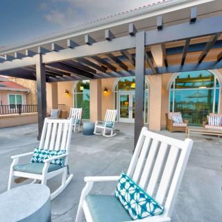 A cozy outdoor patio featuring rocking chairs and a pergola.
