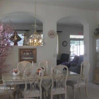 A well-decorated dining room featuring a chandelier, table, and chairs, visible through an archway.