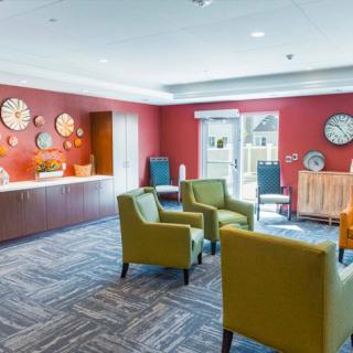 A cozy lounge area with stylish chairs and a collection of decorative clocks on a red accent wall.