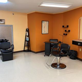 A modern and minimalistic hair salon setup featuring sleek furniture and vibrant orange walls.
