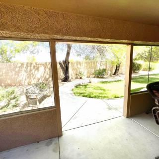 A view from a screened porch overlooking a garden with trees and a well-maintained lawn.