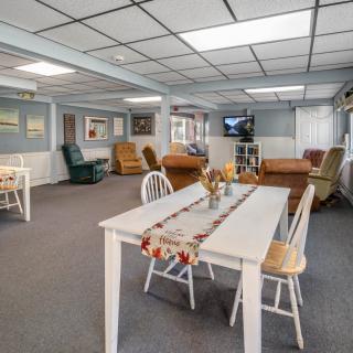 A spacious basement living and dining area with comfortable seating and a television.