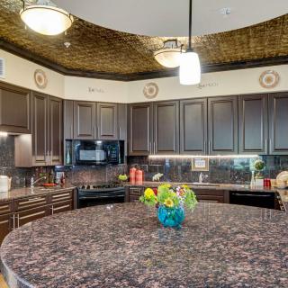 A modern kitchen with dark cabinetry, granite countertops, and stylish lighting fixtures.