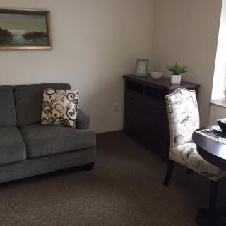 A cozy living room with a sofa, armchair, and decorative elements.