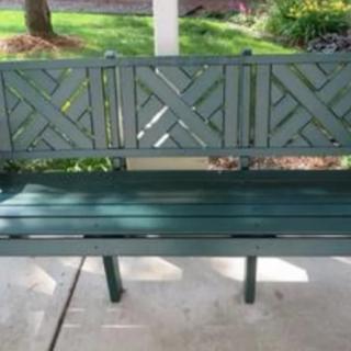 A green wooden bench in a garden setting.