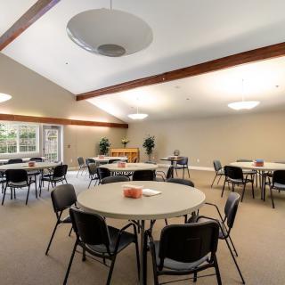 An empty conference room with round tables and chairs arranged for a meeting.