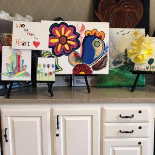 A collection of colorful artwork displayed on small easels atop a cabinet.