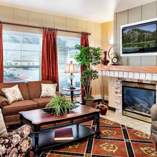 A cozy living room with a fireplace, comfortable seating, and a TV mounted above the mantel.
