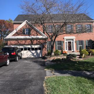 A charming two-story brick house with a well-maintained front yard and a double garage.