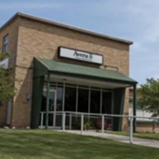 A small brick restaurant building with a green awning and a sign above the entrance.