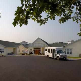 A residential building with a van parked in the driveway surrounded by trees.