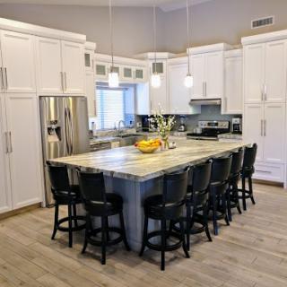 A contemporary kitchen featuring an island with seating, modern appliances, and elegant white cabinetry.