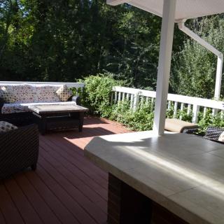 A sunny outdoor deck with comfortable seating and lush greenery.