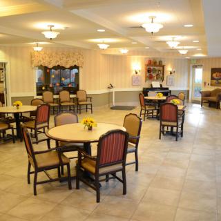 A well-lit dining area with round tables and chairs arranged neatly.