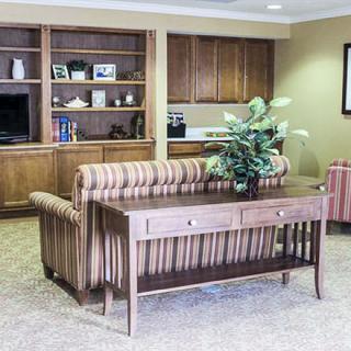A cozy living room with a sofa, wooden bookshelf, and decorative plant.