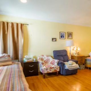 A cozy bedroom with comfortable seating and soft lighting, featuring a bed and armchairs.
