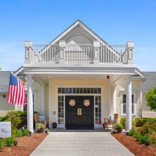 A beautifully designed building entrance with an American flag and well-maintained landscaping.