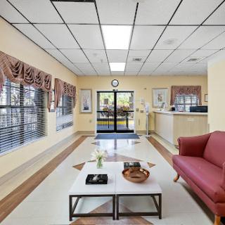 A spacious and welcoming lobby area featuring a comfortable sofa, coffee table, and large windows.