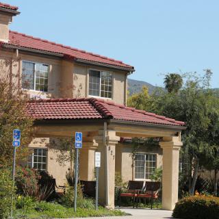 A suburban house with a red-tiled roof and columns at the entrance.