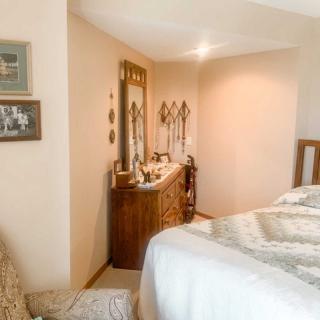 A cozy bedroom with a dresser and mirror, featuring soft lighting and tasteful decor.