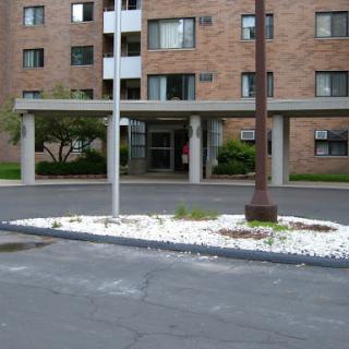 The entrance of an apartment building with landscaped surroundings.