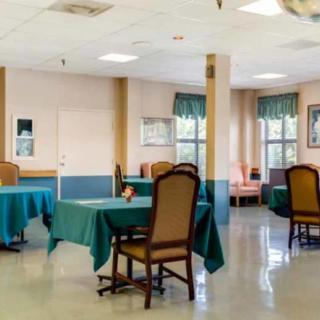A spacious dining area with tables and chairs set up, featuring large windows with curtains.