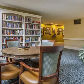 A cozy library reading area with bookshelves, a round table, and chairs.
