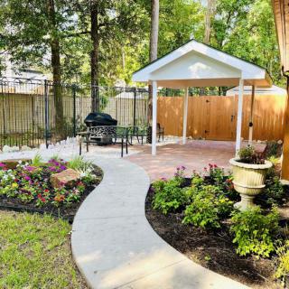 A beautifully landscaped garden with a winding pathway leading to a small pavilion, surrounded by lush greenery and flowers.