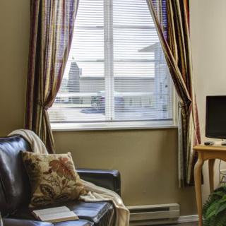 A cozy living room with a sofa and television, featuring a window with striped curtains.