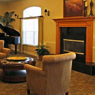 A cozy living room featuring a grand piano, comfortable seating, and a fireplace.
