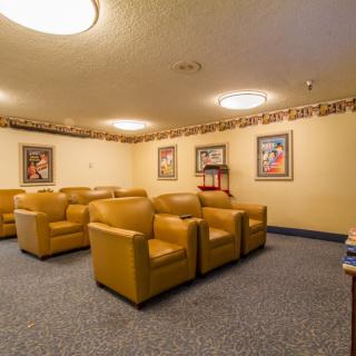 A comfortable seating area with multiple chairs, framed art on the walls, and soft lighting.
