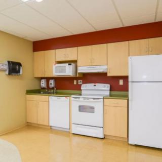 A modern kitchen with wooden cabinets and standard appliances, including a refrigerator, oven, and microwave.