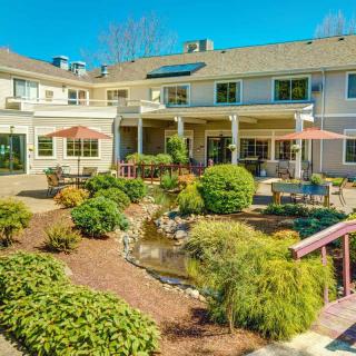 A scenic garden area with lush greenery and a patio outside a two-story building.