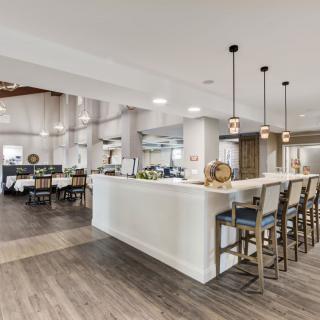 A modern kitchen with a spacious open layout, featuring a central island with barstools and elegant pendant lighting.