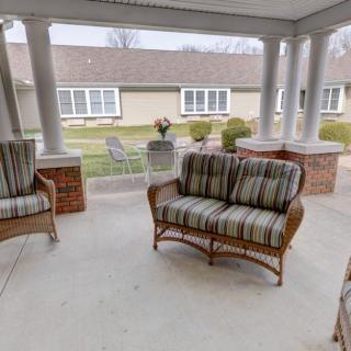 A cozy patio with wicker furniture and cushions, providing a comfortable outdoor seating area.