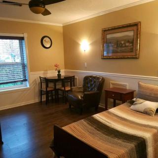 A cozy bedroom featuring a bed, chair, table, and wall decorations.