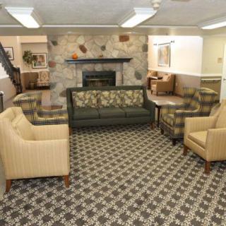 A cozy living room with various sofas and chairs around a stone fireplace, featuring patterned carpet.