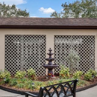 A tranquil garden area featuring a tiered fountain, surrounded by greenery and lattice panels.