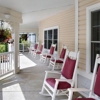 A serene porch featuring red rocking chairs and hanging flower baskets.