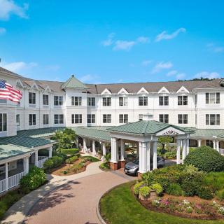 A grand hotel entrance with lush landscaping and an American flag flying above.