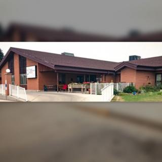 A brick house with a pitched roof and fenced yard.
